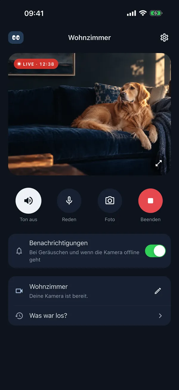 Livebild in der App: Wohnzimmer mit Hund, darunter Tasten für Ton, Gegensprechen und Beenden.